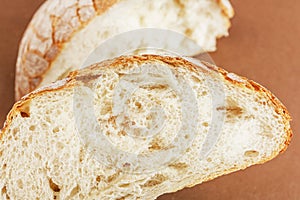 A slice of white fresh crispy bread on a brown background