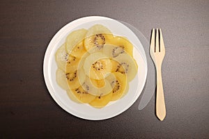 Slice of yellow kiwigold kiwi on plate.