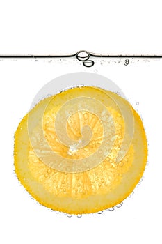Slice of yellow lemon in water with bubbles - isolated