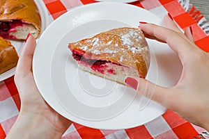 Slice of yummy piece of cherry cake with poedered sugar in woman