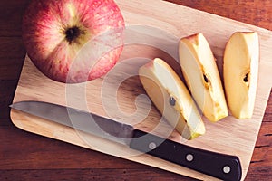 Sliced apple and knife on wooden table