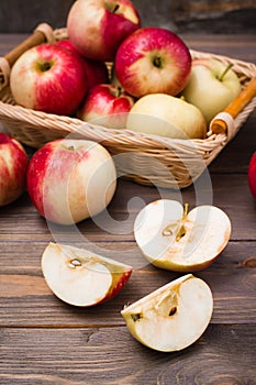 Sliced apple and ripe red apples on a wooden table and in a basket