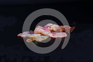 Sliced bacon on a black background. Bacon for burger.