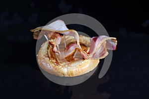 Sliced bacon on a black background. Bacon for burger.