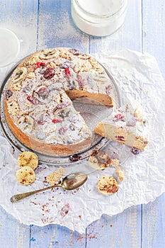 A sliced banana cake with nuts, sesame and cranberry on a wooden