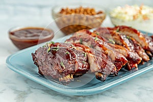 Sliced barbeque ribs on blue plate with side dishes