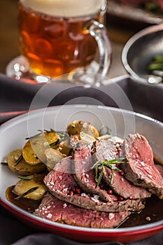 Sliced Beef tenderloin roasted steak potatoes rosemary and draft beer