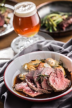 Sliced Beef tenderloin roasted steak potatoes rosemary and draft beer