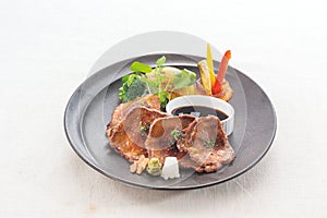 Sliced beef tongue steak Japanese style source on black plate