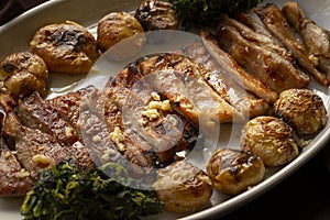 Sliced black pig meat `Secretos de Porco Preto` with smashed potatoes and turnip greens, a typical Iberian plate.