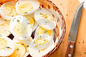 Sliced boiled eggs with dill, kitchen knife close-up