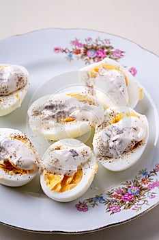 Sliced boiled eggs with mayonnaise and pepper in white plate isolated