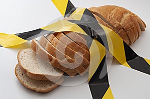 Sliced bread and yellow caution tape isolated on white background concept for food insecurity, hunger warning and hazardous