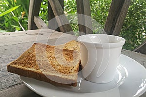 Sliced brown bread toast and coffee on White dish