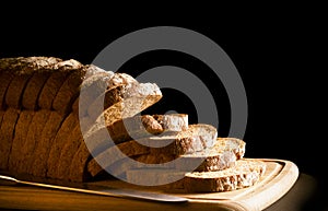 Sliced brown loaf on wooden chopping board