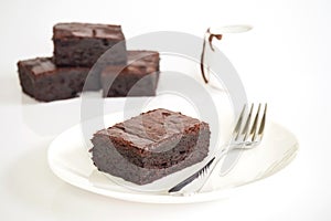 Sliced brownies on white plate. Served with chocolate fudge topp