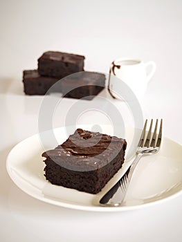 Sliced brownies on white plate. Served with chocolate fudge topp