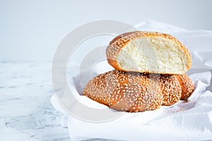 Sliced bun with sesame seeds on a white towel, copy space for your text. Home baking and breakfast concept