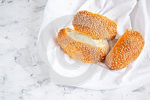 Sliced buns with sesame seeds on a white towel top view. Home baking and breakfast concept. Copy space for your text