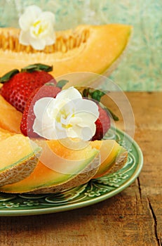 Sliced Cantaloupe, Strawberries, and Flowers.