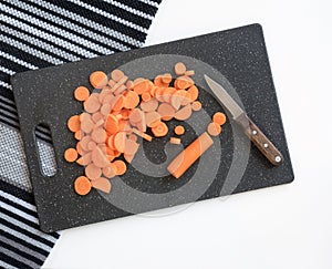 Sliced Carrots with Paring Knife on Black Cutting Board