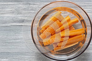 Sliced carrots soaking in a glass bowl of water.