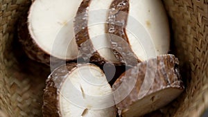 Sliced cassava yucca rhizomes falling into a rustic bowl in slow motion.