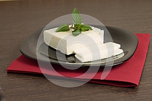 Sliced cheese on black dish with napkin