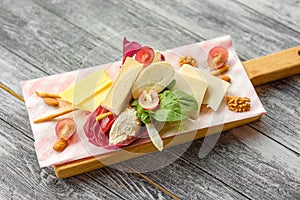 Sliced Cheese with walnuts and grapes on cutting board on wooden background