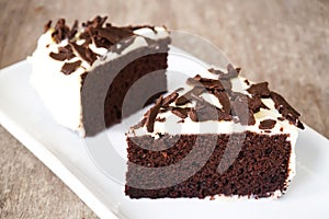 Sliced Chocolate cake decorate with whipping cream, sliced chocolate on white plate. Sweet dessert for celebrate.