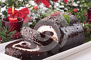 Sliced Christmas yule log cake on plate with candle photo
