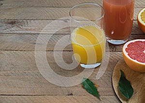 Sliced citrus fruits and citrus juices on a wooden table, orange and grapefruit