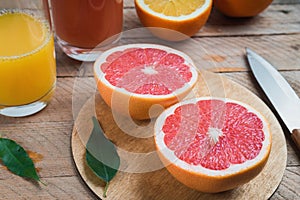 Sliced citrus fruits and citrus juices on a wooden table, orange and grapefruit