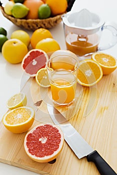 Sliced citrus fruits and glass of fresh orange juice on the cutting board