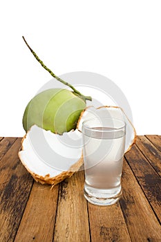Sliced coconut with coconut juice on wooden table with sea view