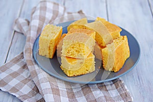 Sliced cornbread on a gray plate on a light wooden background. Corn flour recipes. C