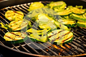 sliced courgettes in a grill basket over barbecue flames