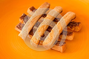 Sliced crispy bread in orange ceramic dish.