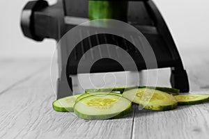 Sliced cucumber with mandoline on a grey wood kitchen worktop