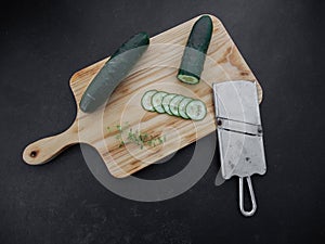 Sliced cucumber with mandoline on a wooden board photo