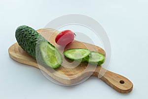 Sliced cucumber, red tomato and a cutting board on white backgr