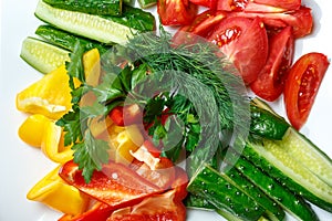 Sliced cucumbers, tomatoes, yellow and red peppers with dill