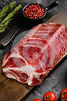 Sliced cured coppa ham, on black dark stone table background