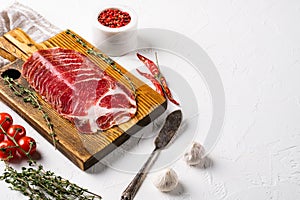 Sliced cured coppa ham, on white stone table background, with copy space for text