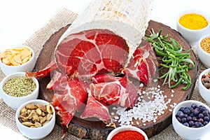 Sliced cured coppa with a sprig of rosemary.
