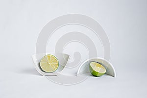 Sliced cut â€‹â€‹halves of lime in a broken half of a ceramic small platter on a white background. Place for text. Concept