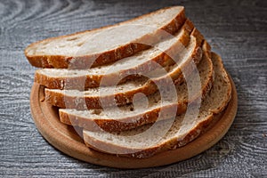 The sliced dark rye bread on wooden plate in rustic style.