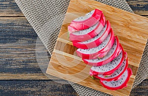 Sliced dragon fruit with cutting board on wooden and placemat background, flat lay