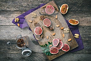 Sliced figs, nuts and bread with jam on choppingboard in rustic