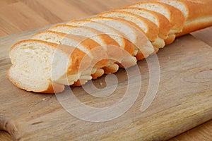 Sliced french bread on cutting board on wooden table